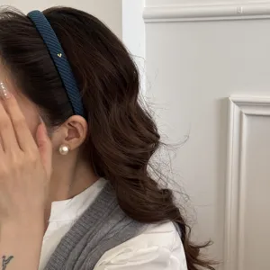 Dettaglio di un elegante cerchietto blu a maglia con un piccolo cuore dorato lucido
