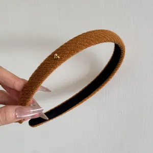 Primo piano di un cerchietto lavorato a maglia color caramello con cuore d'oro