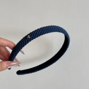 Vista dettagliata del cerchietto in maglia blu con piccolo cuore dorato e trama a costine