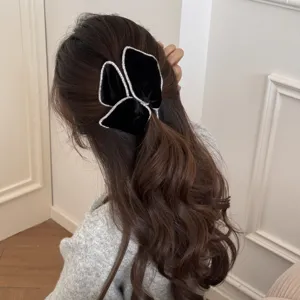 Detail of a black velvet bow hair tie with rhinestone edges worn on a low ponytail.