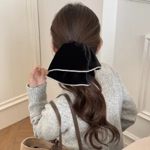 Back view of a woman wearing a black velvet rhinestone-trimmed scrunchie in a low ponytail