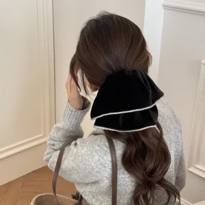 Detail view of an elegant black velvet hair scrunchie with rhinestones on a ponytail.