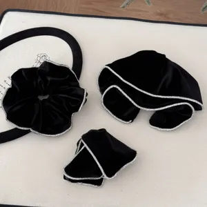 Detailed view of elegant black velvet hair scrunchies and bows with sparkling rhinestone edges.