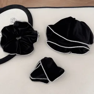Detailed view of black velvet hair scrunchie and clips with sparkling rhinestone edges