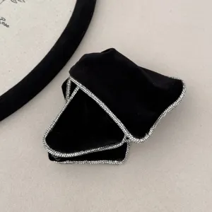Detailed view of luxury black velvet hair scrunchie with shimmering rhinestone edges