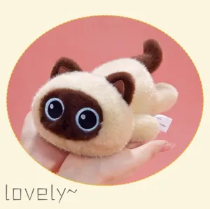 Close-up of a cute plush Siamese cat toy with big eyes in a lying pose, soft texture.