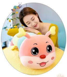 Close-up of a colorful caterpillar plush pillow used by a model in a cozy setting