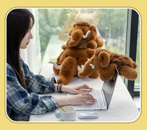 Realistische Mammut Plüschtiere auf einem Schreibtisch neben einer Person am Laptop