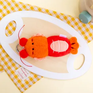 Macro detail of a cute orange and red plush lobster toy keychain on a wooden tray
