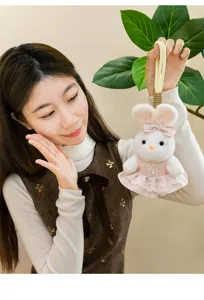 Macro view of cute plush rabbit pendant wearing a pink lace dress with bow accessory