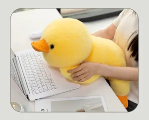 Detailed view of a soft yellow duck plush toy in lying posture used as a desk companion