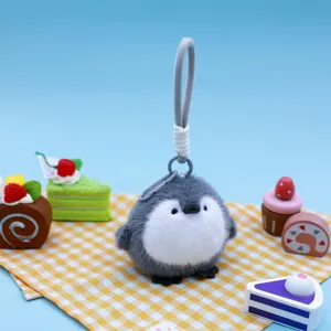 Cute plush penguin keychain charm displayed on a yellow checkered picnic backdrop