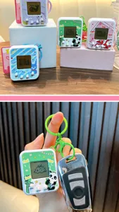 Mini electronic pet machine keychain showing compact size compared to a car key