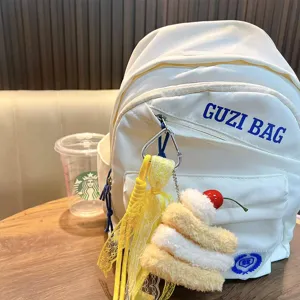 Cute plush hamburger keychain with yellow lace ribbon pendant hanging on a white backpack