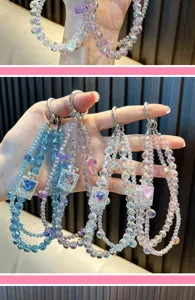 Detailed view of crystal beaded phone straps with heart-shaped perfume bottle charms.