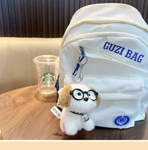 Detailopname van een pluche hondenknuffel sleutelhanger aan een rugzak