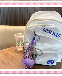 Detail shot of a purple heart keychain with metallic bow on a white backpack