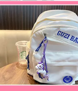 Dettaglio di un portachiavi a forma di cavallo viola e bianco su uno zaino bianco