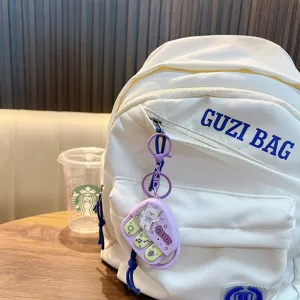 Mini porte-clés jouet enregistreur violet avec musique sur un sac à dos blanc