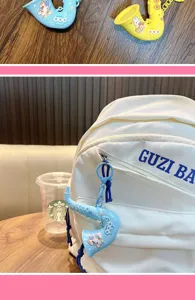 Detalle del llavero de saxofón azul pastel colgado en una mochila blanca moderna