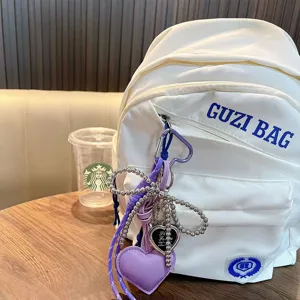 Purple heart keychain bag charm with silver butterfly bead detail on white backpack