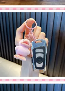 Pink flocked duck keychain accessory shown with a car key on a textured background