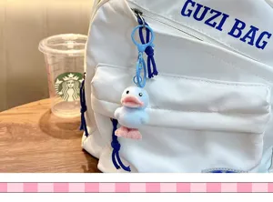Detailed close-up showing a blue flocked cartoon duck keychain attached to a white backpack