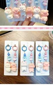 Close-up of cute rabbit and pig phone charms featuring colorful bead accents and cute slogans