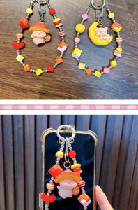 Close-up detail showing the colorful beads and pig charms attached to a smartphone case