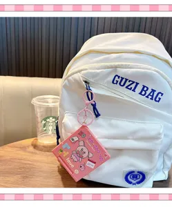 Vista detallada de un llavero de rompecabezas de cerdo rosa colgado en una mochila blanca