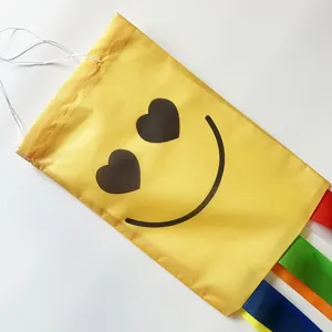 Gelbe Windsack-Flagge mit Herz-Smiley und bunten Regenbogen-Streamern für Garten