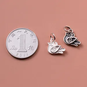 Detailed view of S925 silver bird pendants showing scale next to a reference coin