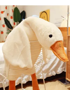 Primo piano di un grande cuscino di peluche a forma di oca bianca su una sedia in camera.