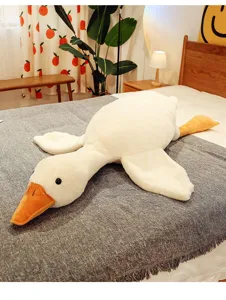 Grande cuscino peluche a forma di oca bianca su un letto accogliente per dormire bene