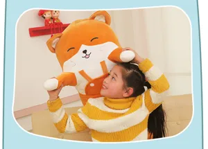 Glückliches junges Mädchen hält ein großes orangefarbenes Fuchs Plüschtier Kissen