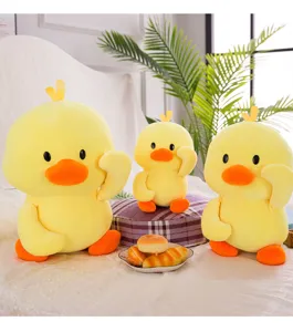Three cute yellow duck plush toys in different sizes displayed on a cozy bed with pastries
