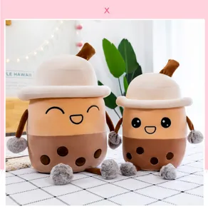 Due simpatici peluche di bubble tea di diverse dimensioni su un accogliente letto bianco