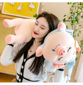 Large sleepy pink pig plush toy with blue nightcap held by a model in home setting