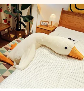 Grande cuscino in peluche a forma di oca bianca su un letto accogliente per dormire
