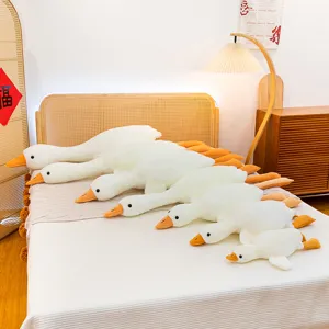 Adorabili cuscini di peluche a forma di oca bianca in varie dimensioni su un letto caldo
