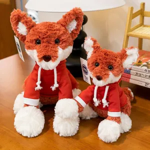 Pair of cute orange fox plush toys wearing cozy red hoodies in a warm setting