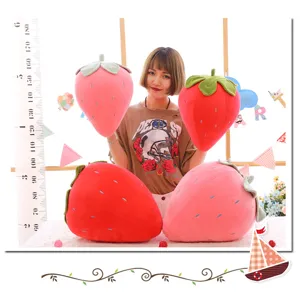 Primo piano di grandi cuscini di peluche a fragola in rosso e rosa con modella
