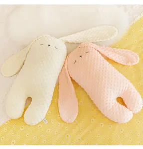 Primo piano di cuscini di peluche a forma di coniglio minky rosa e crema su sfondo floreale
