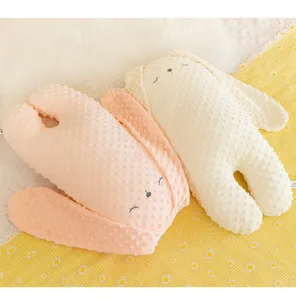 Primo piano della morbida texture in velluto a bolle dei cuscini di peluche a coniglio.