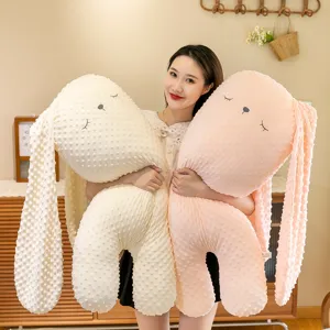 Grandi cuscini di peluche a forma di coniglio in pile a bolle rosa e crema tenuti da modella