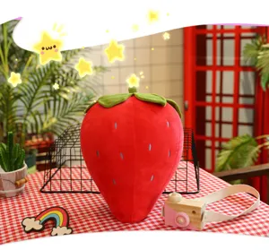 Vista dettagliata di un grande cuscino di peluche a forma di fragola rossa su un tavolo