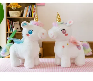 Primo piano di due teneri unicorni di peluche bianchi con corni dorati e criniera arcobaleno