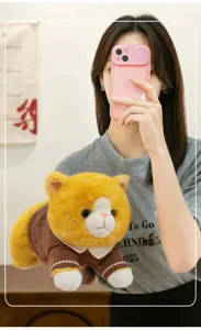 Detail of a chubby orange plush cat toy dressed in a cozy brown knitted sweater