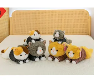 Collection of various cute cat plush toys wearing knitted sweaters on a cozy bed, detail view