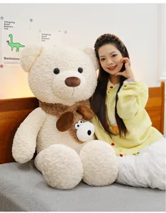 Detalle de un gran oso de peluche crema con bufanda en un dormitorio con una modelo.